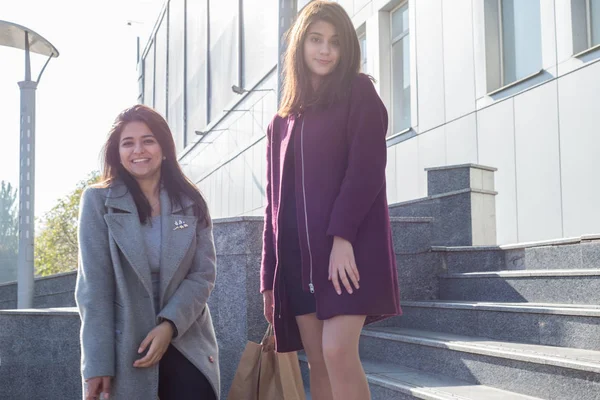 Dos hermosas chicas indias sonrientes hermanas, con bolsas de compras ecológicas, en medio del hipermercado, bajan las escaleras — Foto de Stock