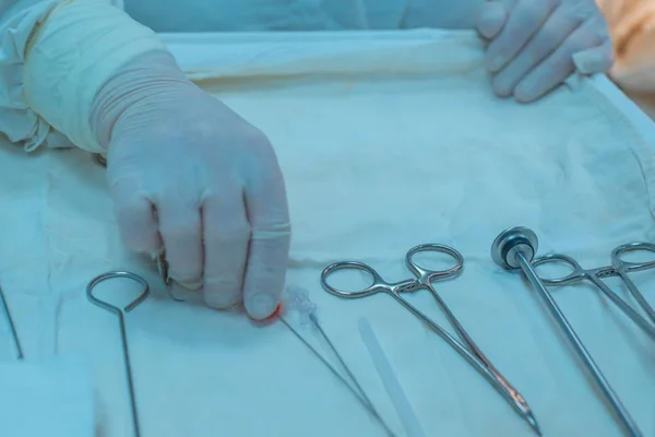 看護師の手 補助外科医は滅菌テーブルから手術器具を取ります 滅菌手術室で メスで耳の悪性腫瘍を除去 軟部組織を縫合 電気凝固 出血を停止 — ストック写真