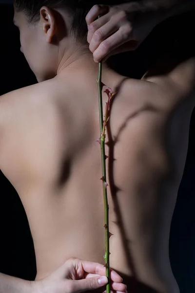 Portrait of a young girl with a stem of thorns of roses behind her, with a background on spinal problems. Back health. Dramatic light. skin cosmetology. Muscle health, scoliosis. kyphosis, lordosis, curvature of the spine, back medicine, spinal colum