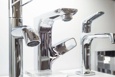 Tezgahtaki beyaz bir rafta çeşitli musluklar var. Musluk musluğu, lavabo ve lavabo için yakın çekim. Hijyen Mühendisliği