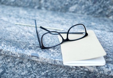 Gözlükler ve bir defter, kalemle, bir ofis binasının merdivenlerinde uzanıyorlar. İş konsepti