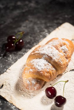 Çilekli, kirazlı kruvasan. Köy tarzında, karanlık soyut bir arkaplanda..