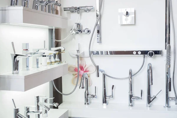 Tezgahtaki beyaz bir rafta çeşitli musluklar var. Musluk musluğu, lavabo ve lavabo için yakın çekim. Hijyen Mühendisliği
