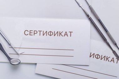 top view, medical dental instruments, on a sterile subject table of a dentist doctor. Against the background of gift certificates for dental services, in Russian.