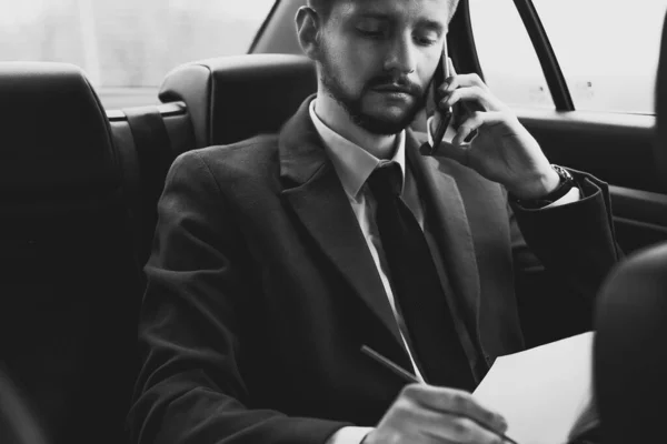 30歳の若い男の肖像画ですビジネススタイルの服のビジネスマン オフィスの助手席に乗って仕事をしたり スマートフォンで問題を解決したり 電話で話しています 若い実業家30歳 スマートフォンを持つスマート男 — ストック写真