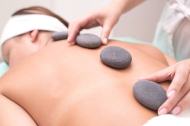 Renkli sırt portresi üzerine spa ameliyatına yakından bakın. Genç bir kadının spa terapisinden büyük keyif alan portresi. Yakın plan. Masaj taşları