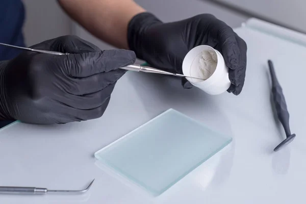 closeup, top view of the dentists hands, in gloves, holding a preparation preparation tool in his hand. Against the background of other dental instruments. Medical flatlay. Prosthetics in dentistry, orthodontics, dental manufacturing, preparation of