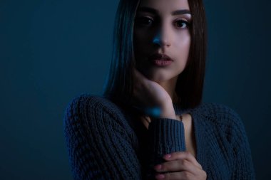 Sanatsal rötuşları olan genç ve güzel bir kızın dramatik bir portresinin sanat stüdyosu. Yakın çekim, kızın yüzü, anlamlı bir bakışla. Karanlık bir arka planda. Hassas bir kızın güzel portresi. Beyaz bir kızın etkileyici yüz hatları var. Modaya uygun.