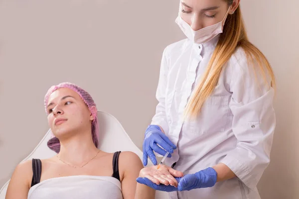 portrait in the cosmetologists office. A young girl in a medical suit, gloves and a syringe performs an injection into the facial and neck muscles to treat wrinkles. scars, muscle spasm, torticolli