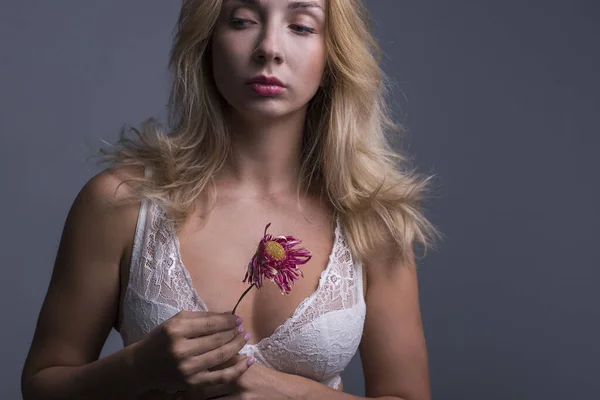 乳腺癌 一个29岁的年轻漂亮的女孩 穿着胸罩 手里拿着一朵枯萎的芙蓉花 在灰色背景上的工作室照片 妇女的乳房疾病 胸部的纤维瘤 乳腺癌 — 图库照片