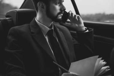 Otuz yaşında genç bir adamın portresi. İş adamı gibi giyinmiş bir iş adamı. Ofiste yolcu koltuğunda çalışıyor, akıllı telefondan sorunları çözüyor, telefonla konuşuyor. Genç iş adamı 30 yaşında. Akıllı telefonlu akıllı adam.