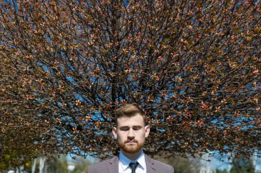 Ağaç uzatan, gözleri kapalı, sakallı bir gencin portresi. Açık havada. Yaratıcı sanatsal tonlamada. İş konsepti. 25 yaşındaki genç bir adamın kafasından çıkan bahar fotoğrafı ağacı, iş konsepti. Düşüncelerin doğuşu,