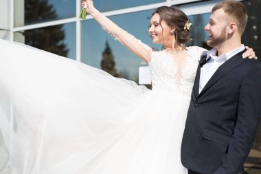 Gelin buketi kaldırır, uçan bir gelinlik, damat gülümser. 25 yaşındaki gülümseyen genç insanlar, düğün töreni, gelin ve damat çifti aşık, gelinlik, erkek takımı. Düğün gününde neşeli evli bir çift, gelin.