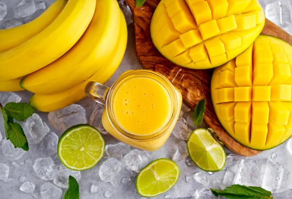 Batido de mango de plátano amarillo saludable con rodajas de lima, menta y hielo —  Fotos de Stock