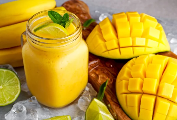 Batido de mango de plátano amarillo maduro saludable con rodajas de lima, menta y hielo —  Fotos de Stock