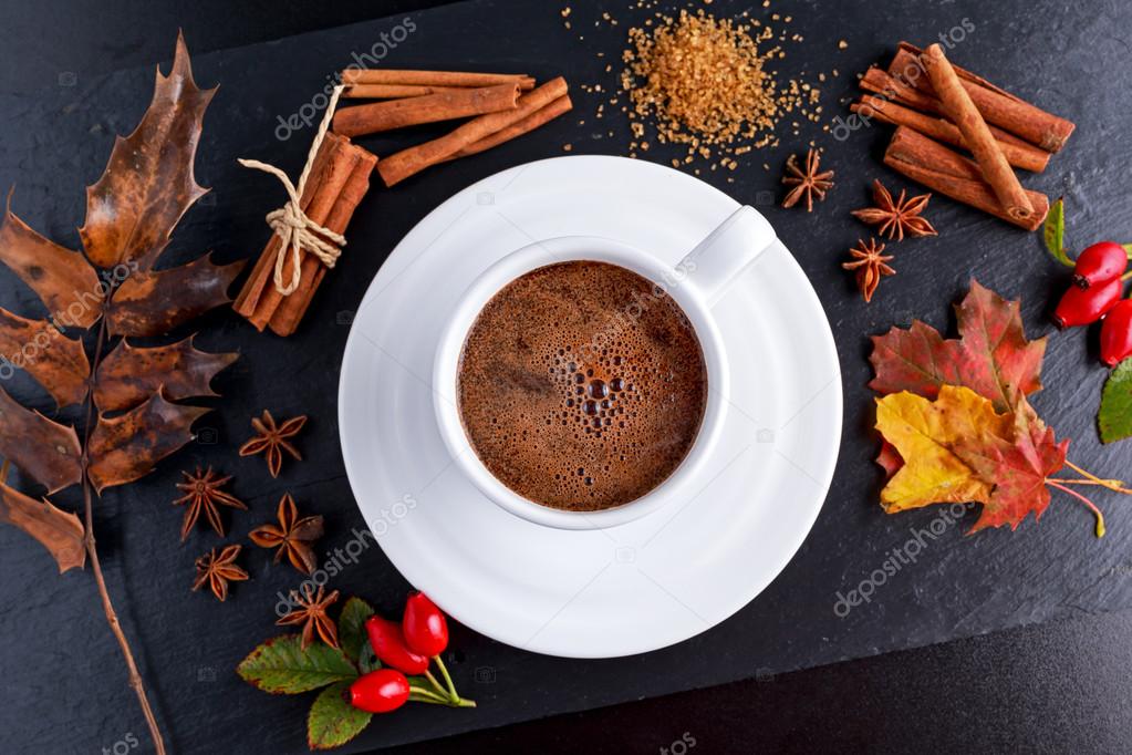 Black hot coffee in white cup with anis stars, brown sugar and cinnamon sticks on stone board autumn theme