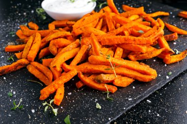 Sağlıklı ev yapımı pişmiş turuncu tatlı patates kızartması ile taze krema sosu, otlar, tuz ve biber daldırma.