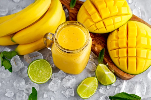 Batido de mango de plátano amarillo maduro saludable con rodajas de lima, menta y hielo —  Fotos de Stock