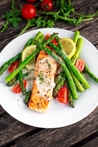 Salmón frito con espárragos, tomates, limón, lima amarilla en plato blanco — Foto de Stock