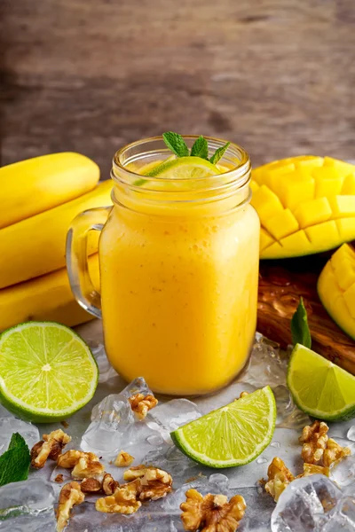Batido de mango de plátano amarillo maduro saludable con rodajas de lima, menta y hielo —  Fotos de Stock