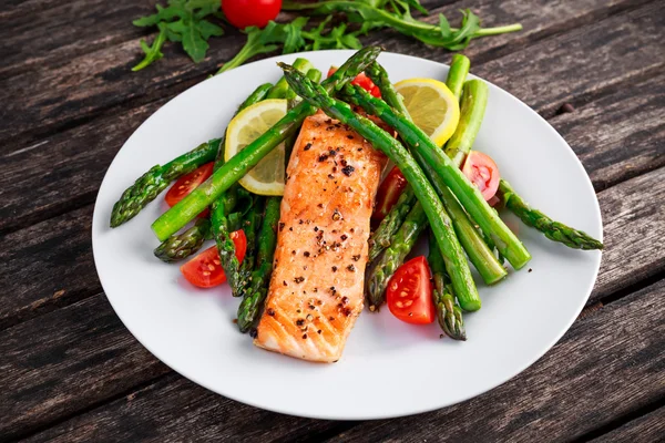 Salmón frito con espárragos, tomates, limón, lima amarilla en plato blanco —  Fotos de Stock