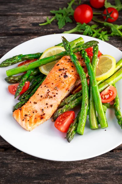 Fried salmon with asparagus, tomatoes, lemon, yellow lime on white plate — Stock Photo, Image