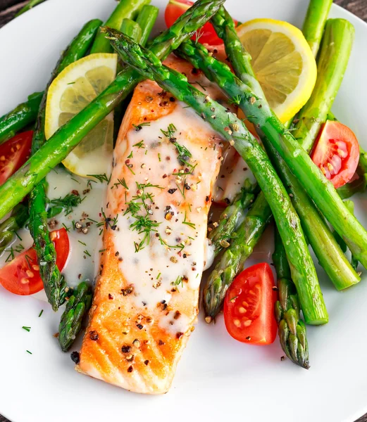 Fried salmon with asparagus, tomatoes, lemon, yellow lime on white plate — Stock Photo, Image