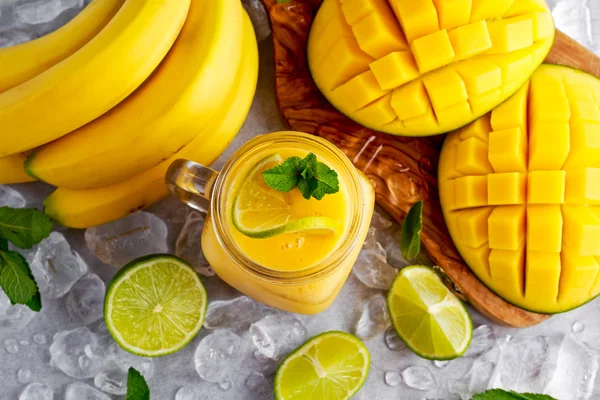 Batido de mango de plátano amarillo maduro saludable con rodajas de lima, menta y hielo —  Fotos de Stock