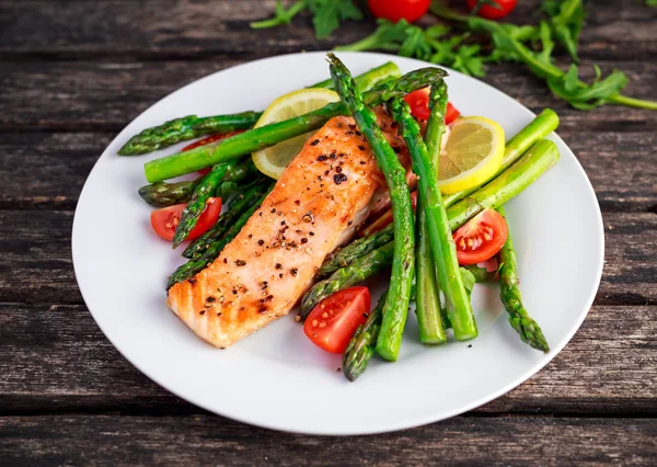 Fried salmon with asparagus, tomatoes, lemon, yellow lime on white plate — Stock Photo, Image