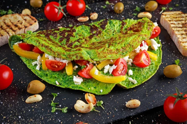 Warzywa zielone omlet z pomidorów, grecki ser, oliwki, orzechy, papryka, toast na kamienne podłoże. Zdrowe jedzenie koncepcja. — Zdjęcie stockowe
