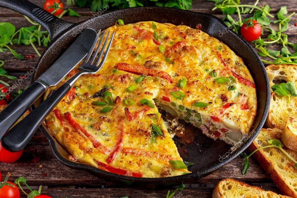 Frittata made of eggs, potato, bacon, paprika, parsley, green peas