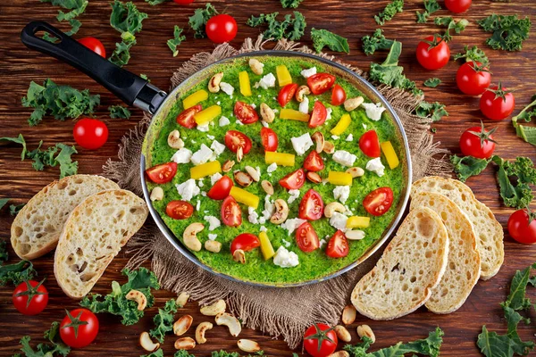 Omelette verde vegetale con pomodori, cavolo, formaggio greco, olive, noci, pane tostato su fondo di legno. concetto cibo sano — Foto Stock