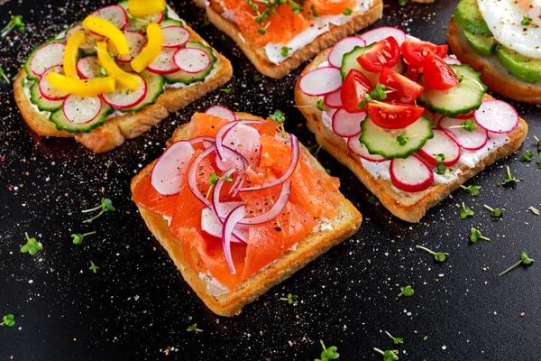 Varietate de sandvișuri de pâine prăjită vegetariene cu somon, raddish, roșii, castravete, avocado, ou prăjit și piper dulce — Fotografie, imagine de stoc