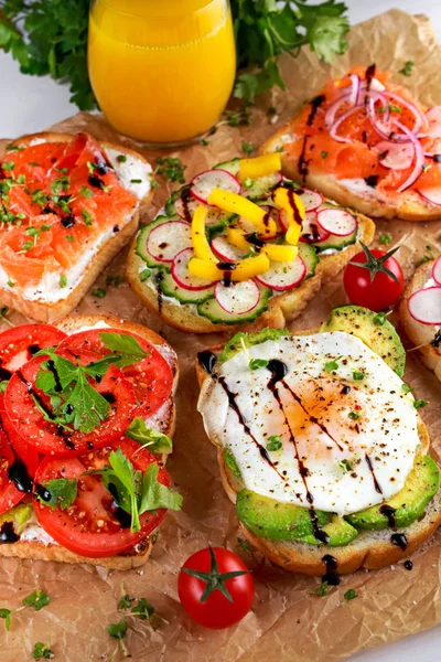 Variety of vegetarian toast sandwiches with salmon, raddish, tomatoes, cucumber, avocado,fried egg and sweet pepper — Stock Photo, Image