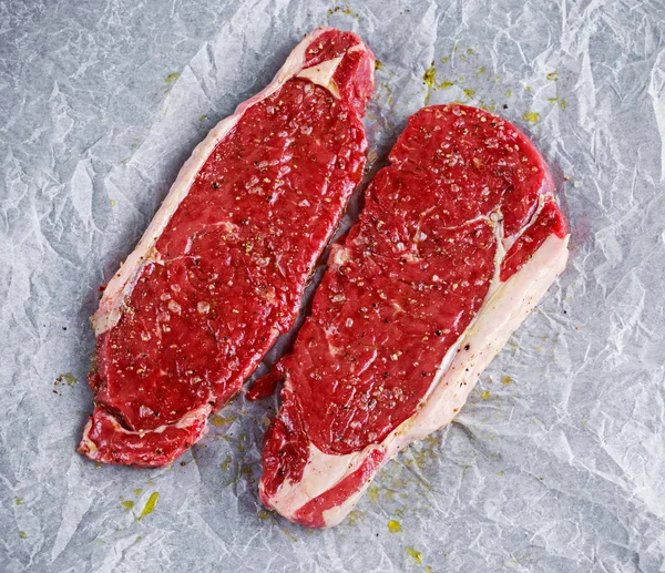 Raw seasoned sirloin prime british steaks on paper — Stock Photo, Image