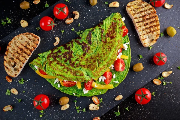 Vegetais Omelete verde com tomates, queijo grego, azeitonas, nozes, páprica, torrada em fundo de pedra. conceito alimentos saudáveis . — Fotografia de Stock