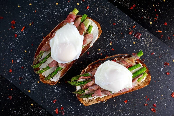 Grilled Toast witch Asparagus, Poached egg, bacon on stone background