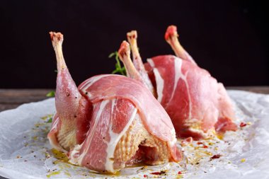 Ready to cook raw seasoned partridges with bacon on crumpled paper. clipart