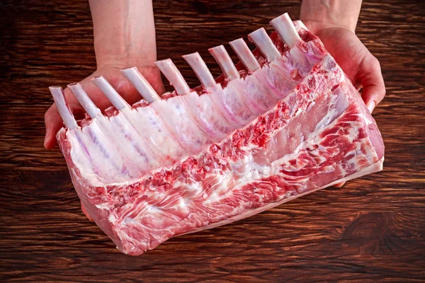 Segar mentah Perancis seluruh rak daging babi dengan tulang rusuk di tangan manusia — Stok Foto