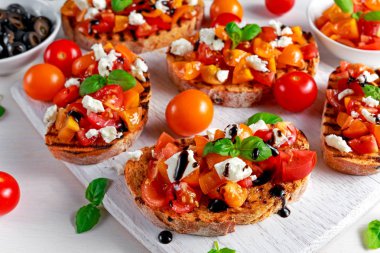 Beyaz peynir tepesi, taze fesleğen ve balsamik sirke ile lezzetli geleneksel domates bruschetta