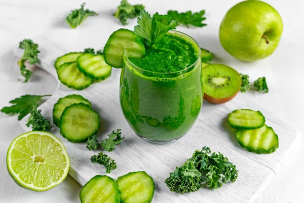 Čerstvý zelený smoothie s kale, okurka, vápno, apple, petržel na bílé desce. — Stock fotografie