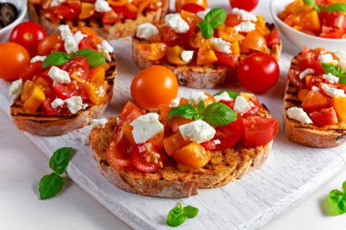 Lezzetli geleneksel domates bruschetta tepesi, taze fesleğen beyaz peynir ile.