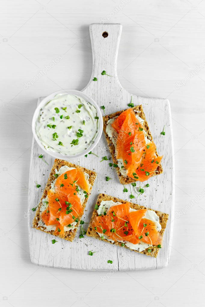 Homemade Crispbread toast with Smoked Salmon, Melted Cheese and cress salad. on white wooden board background.