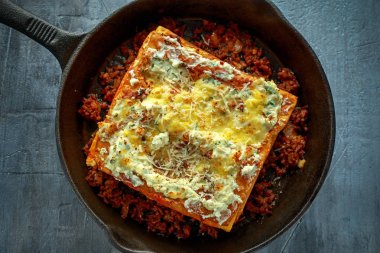 Demir tavada kıyılmış sığır eti bolognese soslu ev yapımı gevrek lazanyaya parmesan peyniri