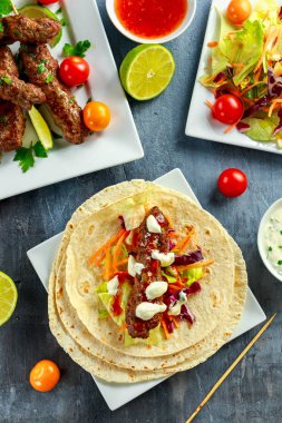 Ev yapımı köfte kebap pide, kireç, sebze, tatlı biber ve yoğurt sos beyaz plaka üzerinde şiş üzerinde