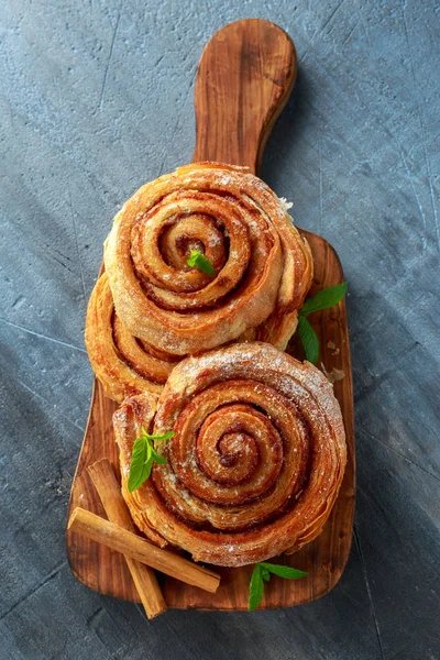Čerstvě upečené tradiční sladké skořice Rolls, krouživým pohybem na dřevěné desce — Stock fotografie