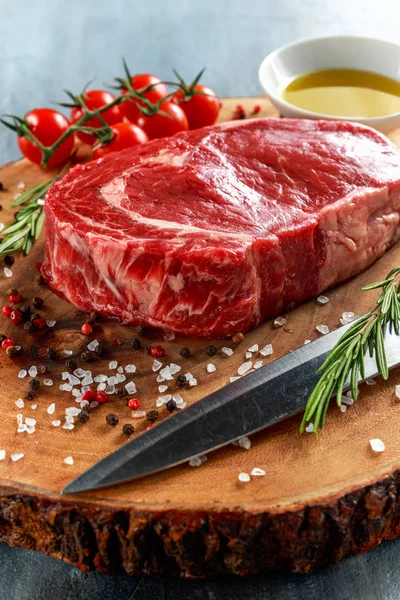 Fresh Raw Beef Steak Ribeye, with salt, peppercorns, rosemary, tomatoes and olive oil — Stock Photo, Image