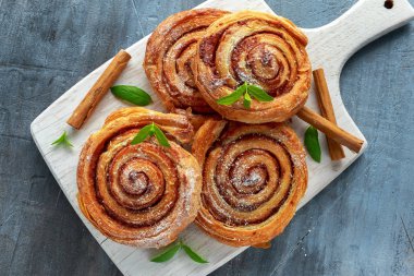 Taze pişmiş geleneksel tatlı tarçın rulo üzerinde beyaz ahşap tahta karıştırıcı