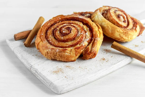 Čerstvě upečené tradiční sladké skořice Rolls, krouživým pohybem na dřevěné desce bílé — Stock fotografie