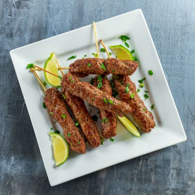 Ev yapımı köfte kebap şişleri kireç ve beyaz tabakta maydanoz üzerinde